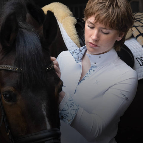 Woman in equestrian attire interacting with a horse