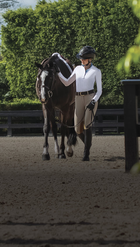 Women dressed in show apparel walking dark bay horse with chrome dressed to show in the hunter ring.